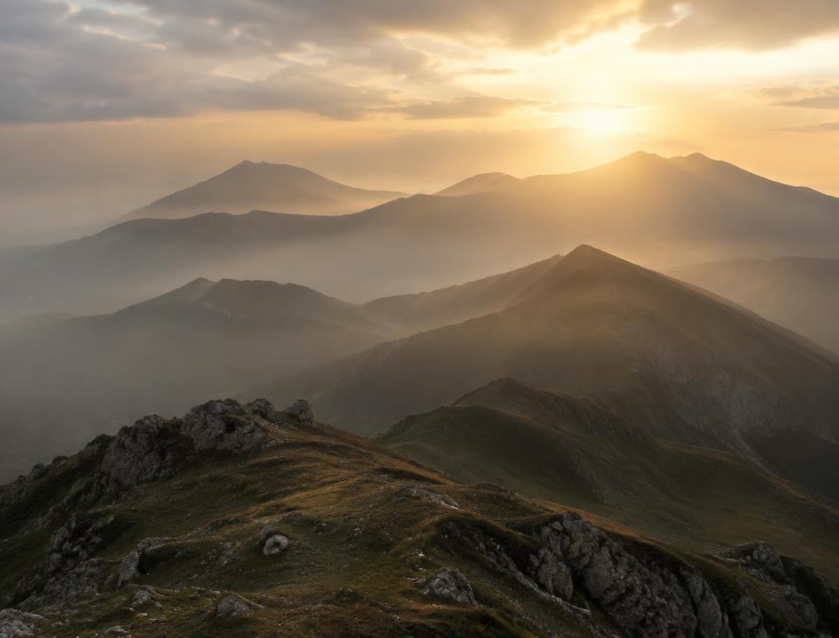 Misty alpine ridge at dawn with layered mountain silhouettes